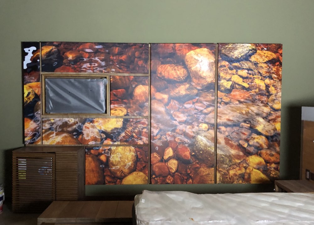 Mural de gran formato en varios paneles con fondo de río y piedras